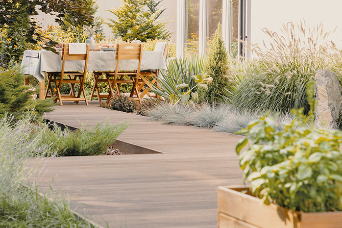 Grande terrasse avec meubles de jardin, bordée de plantes
