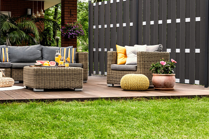 Terrasse en WPC dans le jardin avec sièges, décoration et plantes en bacs
